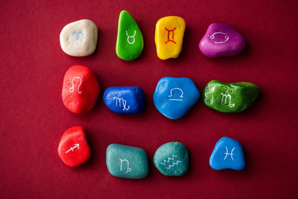 Top view of colorful stones with zodiac signs on red surface